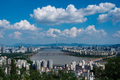 High angle view of city buildings against cloudy sky