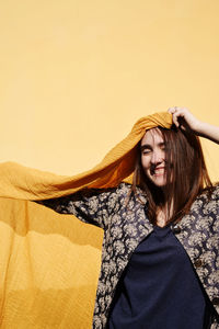 Cheerful woman standing with sarong against beige wall