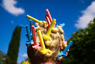 Woman wearing hair curlers against blue sky