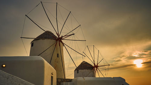 Low angle view of traditional windmill against sky at sunset