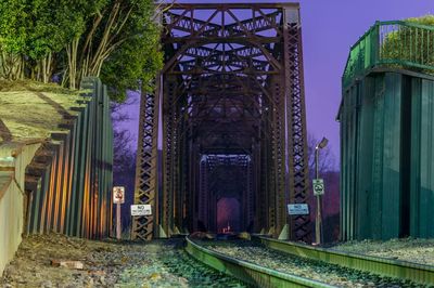 Railroad tracks in metallic tunnel against sky