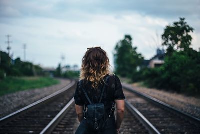 Rear view of people walking on railroad track