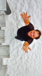 High angle portrait of man with arms raised standing on snow