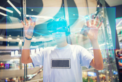 Digital composite image of man wearing virtual reality eyeglasses while standing in shopping mall