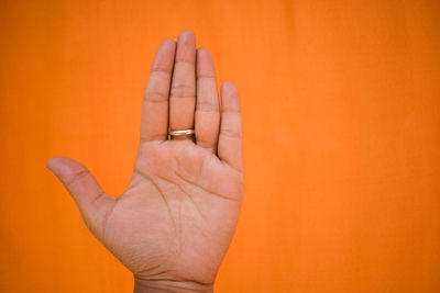 Close-up of human hand against orange background