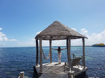 Man standing on pier over sea against blue sky