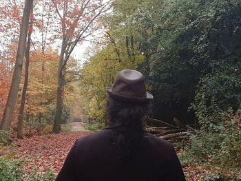 Rear view of woman standing amidst trees in forest