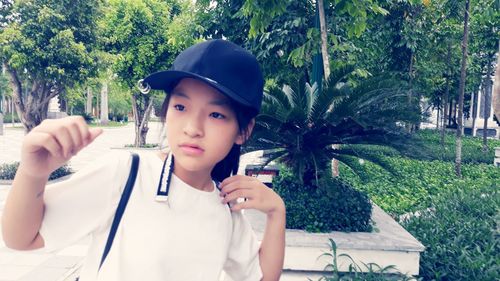 Portrait of girl holding plant against trees