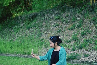 High angle view of young woman taking selfie with smart phone while standing against hill