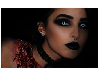 Close-up portrait of young woman against black background