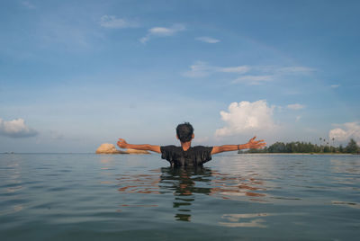 Man standing in sea with arms outstretched