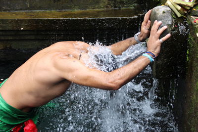 Side view of man standing under flowing water at temple