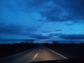 Road against blue sky seen through car windshield