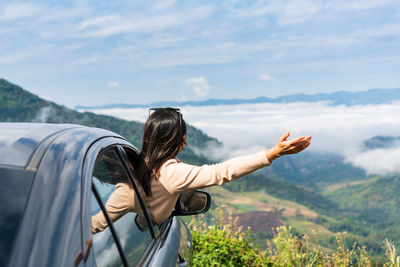 Woman leaning out from car window against landscape