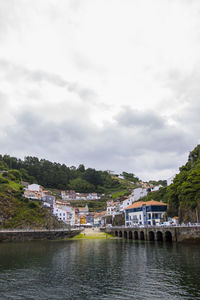 Buildings by river against sky