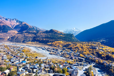 Aerial view of townscape by mountains against clear blue sky