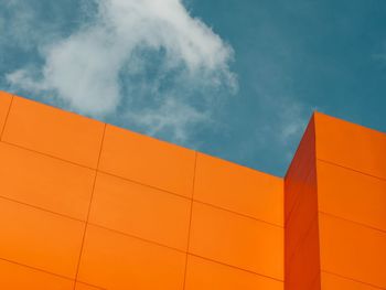 Low angle view of yellow building against cloudy sky