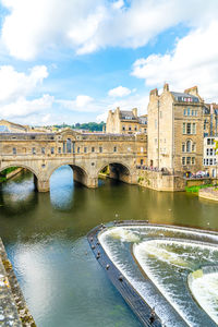 Arch bridge over river against buildings in city