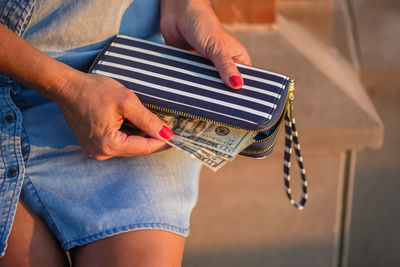 Midsection of woman removing paper currency from purse