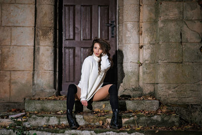 Full length portrait of woman sitting outdoors