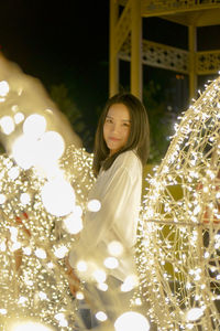 Portrait of woman standing against illuminated lights