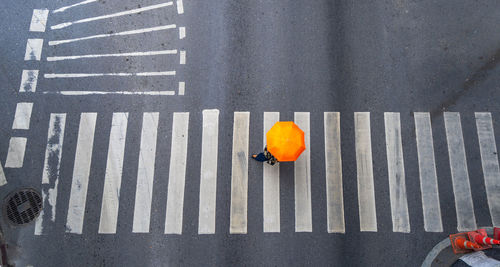High angle view of woman with umbrella crossing road