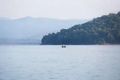 Boat moving on lake against mountains