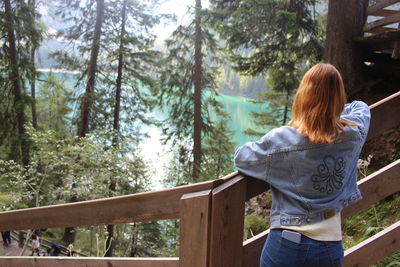 Rear view of woman standing by railing in forest