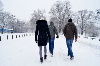 Rear view full length of friends walking on snow covered road