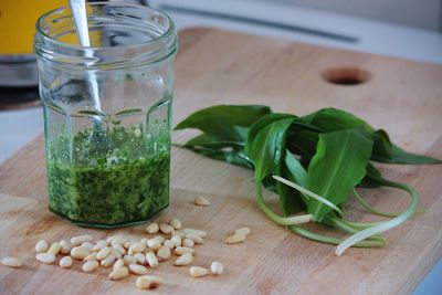 Close-up of pine nuts and ramsons by pesto in jar on cutting board