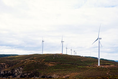 Wind turbines on land against sky