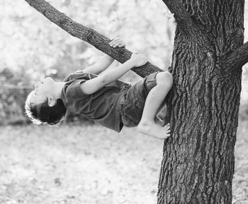 Upside down boy wrapped around tree branch