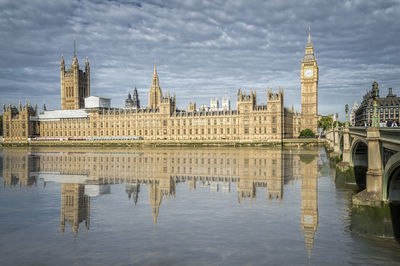 Palace of westminster and big ben reflected on thames river in city