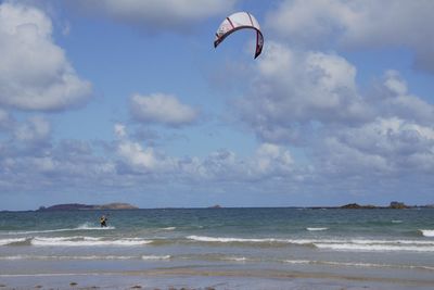 Person paragliding on beach against sky