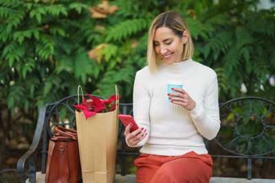 Portrait of smiling young woman holding book while sitting on field