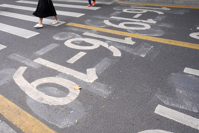 Low section of woman crossing road in city