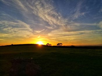 Scenic view of silhouette field against sky during sunset
