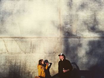 Rear view of people photographing against wall