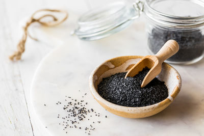 Black hawaiian rock salt in a bowl with a small wooden scoop.