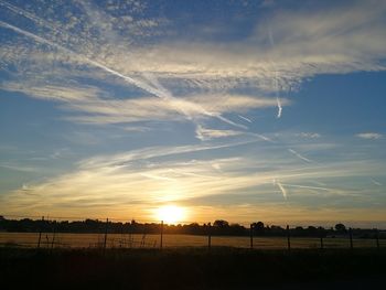 Scenic view of silhouette field against sky at sunset