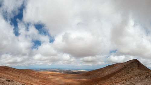 Panoramic view of desert against cloudy sky