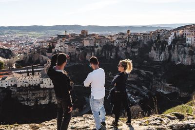 Full length of friends standing on cliff by cityscape