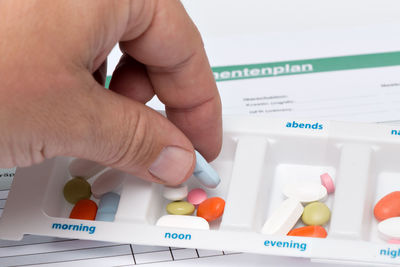 Cropped image of hand with medicines in container