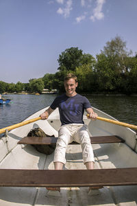 Portrait of young man sitting on boat sailing in river