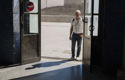 Full length of a man standing in the entrance of a public station in a sunny day