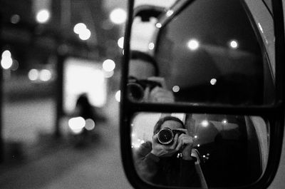 Reflection of man photographing in illuminated camera