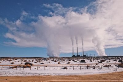 Smoke emitting from chimney on land against sky