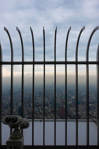 Close-up of railing against sea and cityscape