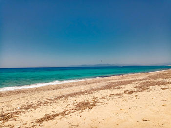 Scenic view of beach against clear blue sky