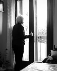 Senior woman standing by door at home
